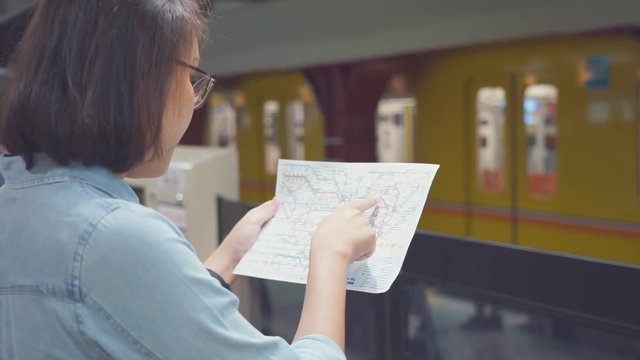 Young Asian woman tourist waiting train at the metro station and looking a metro map to find the right station while traveling in Tokyo Japan.