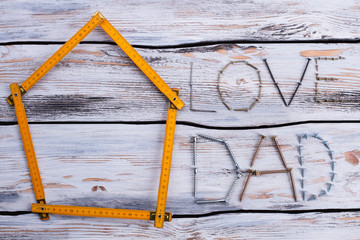 LOVE DAD text on wooden background. Folding ruler in a shape of house and inscription LOVE DAD. Flat lay composition.