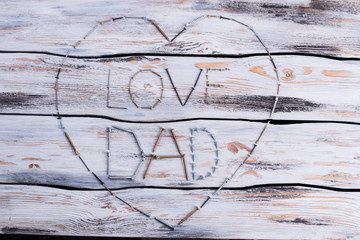 LOVE DAD text and heart made from screws. Composition for Fathers Day on wooden background.