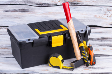 Tool box and different tools on wooden background. Builder ruler, hammer, pliers, screwdriver and tool box. Construction concept.
