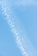Beautiful light blue sky with white clouds and aircraft trail