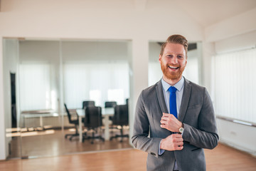 Portrait of a successful redhead millennial businessman in formal wear, smiling at camera.