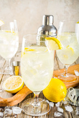 Trendy summer cold drink. St Germain French Spritz cocktail with lemon slices, old rustic wooden background copy space