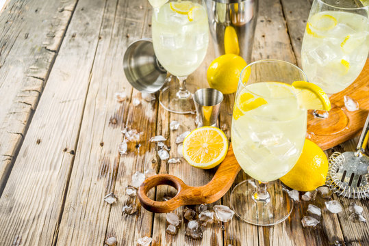 Trendy summer cold drink. St Germain French Spritz cocktail with lemon slices, old rustic wooden background copy space