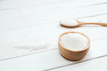 Obraz na płótnie Canvas Sugar is in a wooden bowl on a white table.