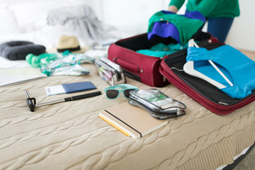 tourism, people and luggage concept - happy young woman packing travel bag at home or hotel room