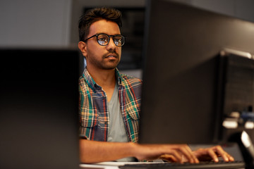deadline, technology and people concept - close up of creative man in glasses working at night...