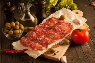 Chorizo sausage and salami, thin cut. spanish salami on the wood background with spices, paprika, pepper. Spicy food. Garlic, tomato, salad background.