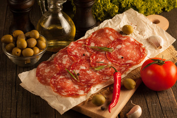 Chorizo sausage and salami, thin cut. spanish salami on the wood background with spices, paprika, pepper. Spicy food. Garlic, tomato, salad background.