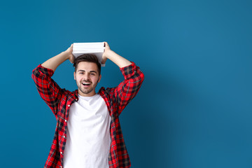 Handsome young man with books on color background