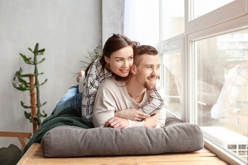 Obraz premium Happy couple resting near window at home