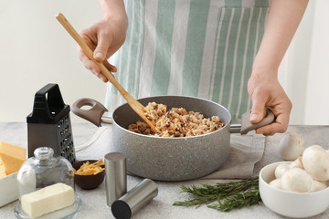 Woman cooking tasty risotto at table