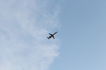 Red plane on cloudy background. Airplane flying in clear pale blue sky.