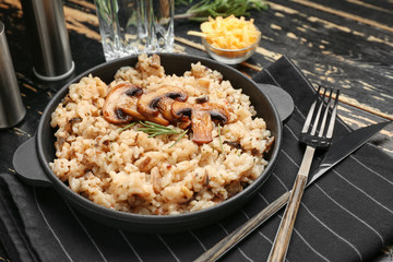 Frying pan with tasty risotto on wooden table