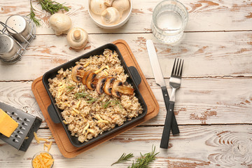 Frying pan with tasty risotto on wooden table