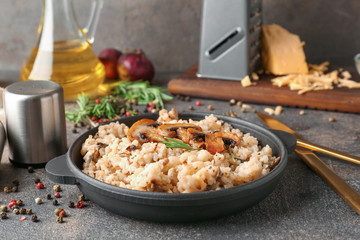 Frying pan with tasty risotto on grey table