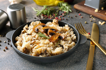 Frying pan with tasty risotto on grey table