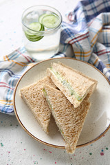 Plate with tasty cucumber sandwiches on light table