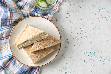 Plate with tasty cucumber sandwiches on light table