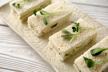 Plate with tasty cucumber sandwiches on white table