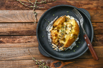 Frying pan with tasty stuffed potato on wooden table