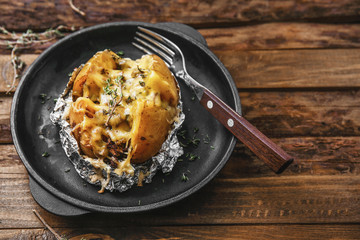 Frying pan with tasty stuffed potato on wooden table