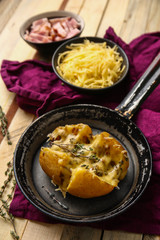 Frying pan with tasty stuffed potato on wooden table
