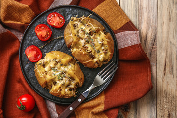 Plate with tasty stuffed potato on wooden table