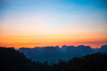 Fototapeta na wymiar Landscape with beautiful dramatic sunset and silhouette of blue mountains at horizon, Thailand