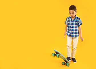 Portrait of cute little boy with skateboard on color background © Pixel-Shot