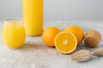 Freshly made orange juice containing vitamin C, sliced oranges, wooden cork and squeezer. Process of making fruit drink. Healthy beverage