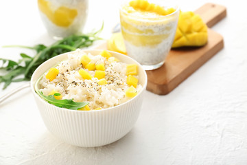 Bowl with tasty rice and mango on white table