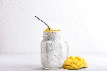 Mason jar of tasty mango dessert on white table