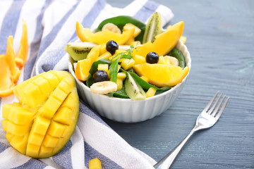 Bowl with tasty mango salad on wooden table