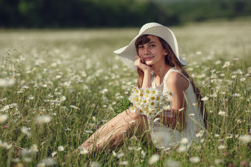 Obraz premium Little girl in a field of daisy flowers