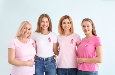 Beautiful women of different ages with pink ribbons on light background. Breast cancer concept