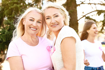 Beautiful mature women with pink ribbons outdoors. Breast cancer concept