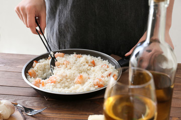 Woman cooking tasty risotto at table