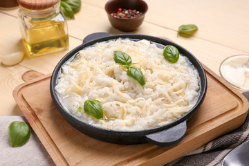 Frying pan with tasty risotto on wooden table