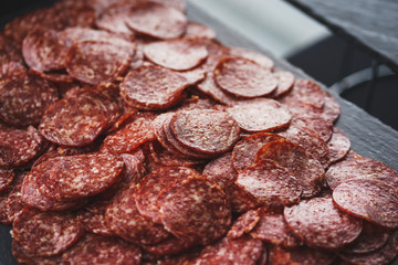 Thinly sliced sausage slices on a black stone board. 