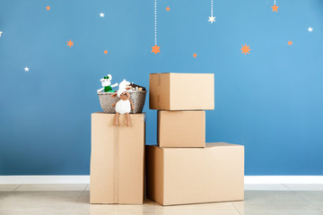 Cardboard boxes with belongings prepared for moving into new house near color wall