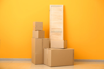 Cardboard boxes with belongings prepared for moving into new house near color wall