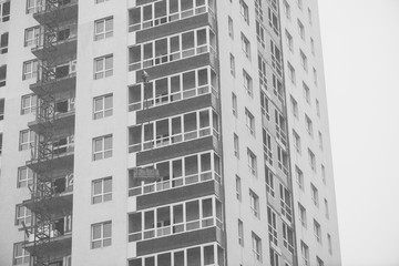 Monochrome concept of apartment building under construction close-up. Exterior of new multi-story residential building in grayscale. Background with walls, plastic windows and loggias. Copy space.