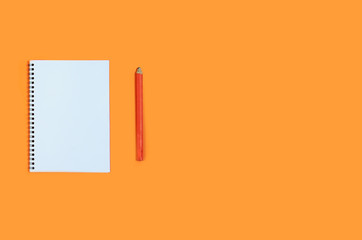 Top view blank notebook with pencil on orange background. Minimal office desk workplace. copy...