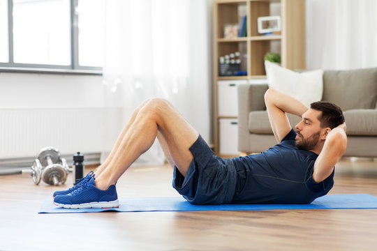 sport, fitness and healthy lifestyle concept - man making abdominal exercises at home