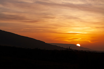 LANDSCAPE OF SUNSET BEHIND THE MOUNTAINS AND ILLUMINATED HEAVEN