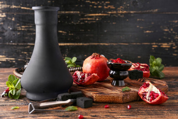 Hookah with tobacco, coal and fresh pomegranate on table
