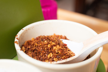Macro closeup of Thai chili powder in the white ceramic cup with spoon at resterant.