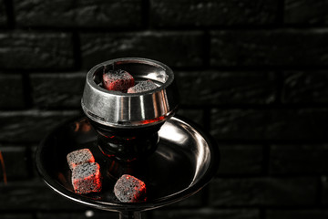 Burning coal for hookah on black brick background