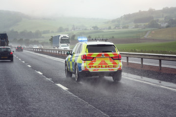 Police siren flashing blue lights on motorway in bad weather conditions